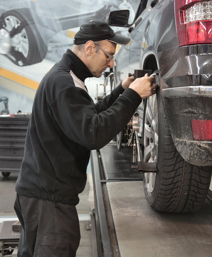 mobile-02 Side view of a mechanic aligning a car tire in a professional auto workshop.