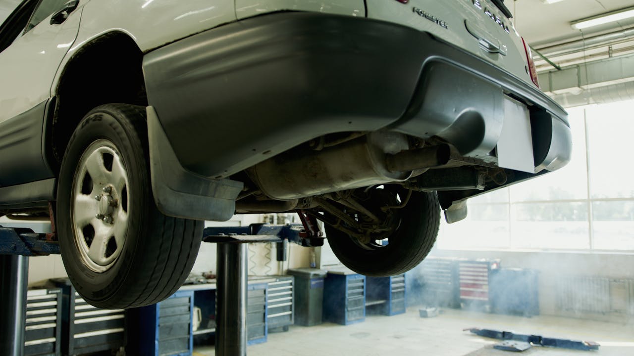 creative-02 A vehicle elevated on a lift in an auto repair shop, ready for service.